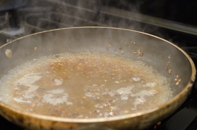 Stock, butter and wine simmering to make a pan sauce