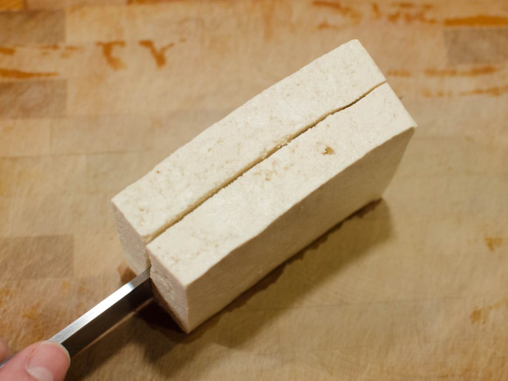 Extra Firm Tofu being sliced in half